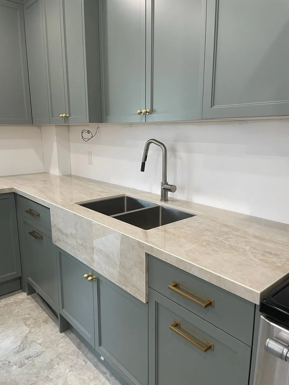 Modern blue-grey kitchen cabinetry with brass hardware and a stone counter