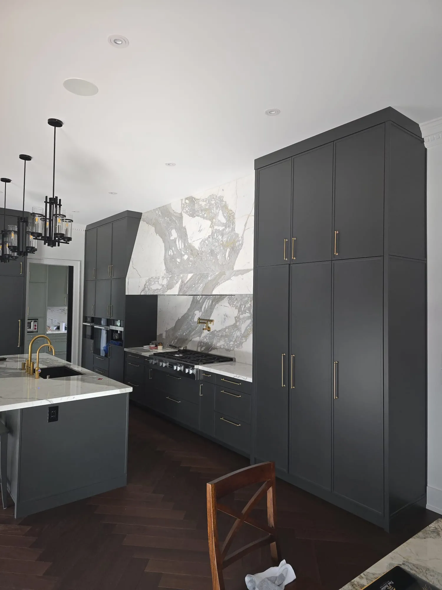 Charcoal custom kitchen with a large marble island and brass fixtures