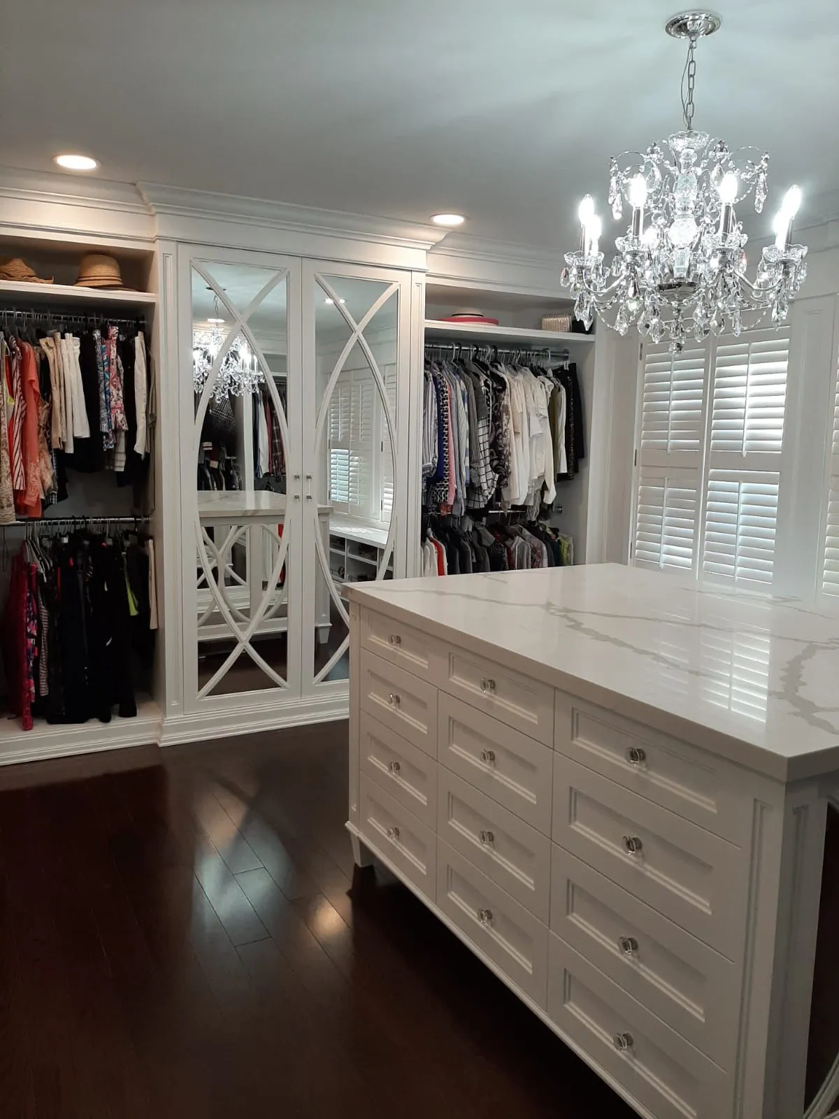 White dressing room cabinetry with glass doors and a centre island