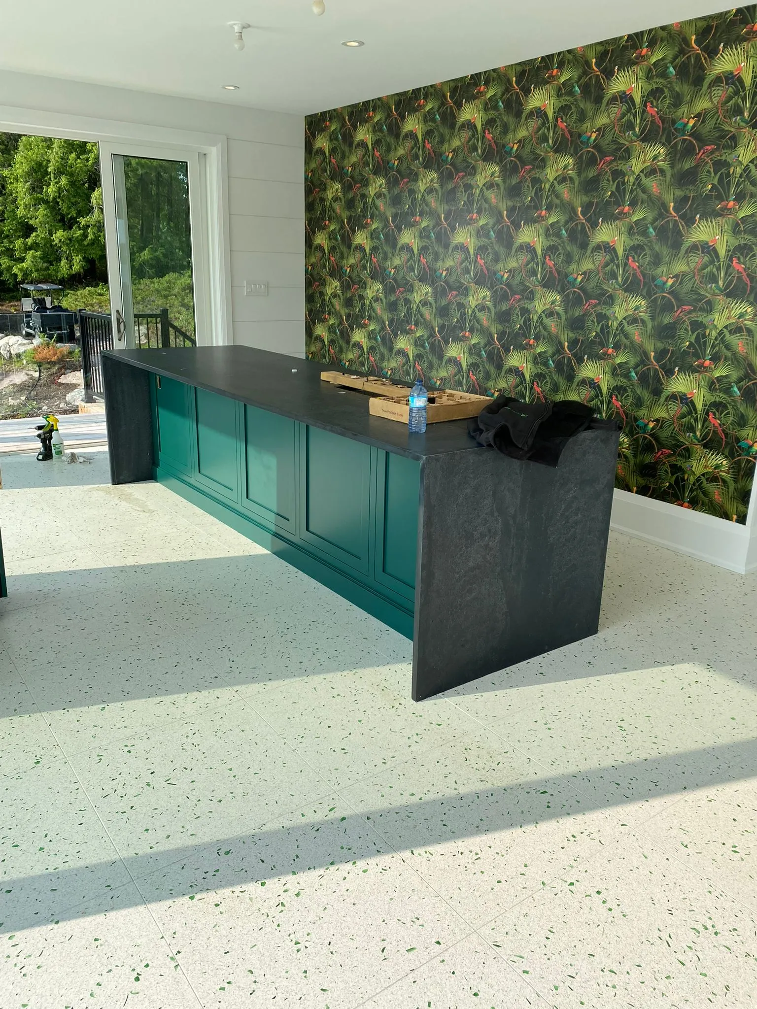 Deep green bar cabinet with open shelving and a stone counter
