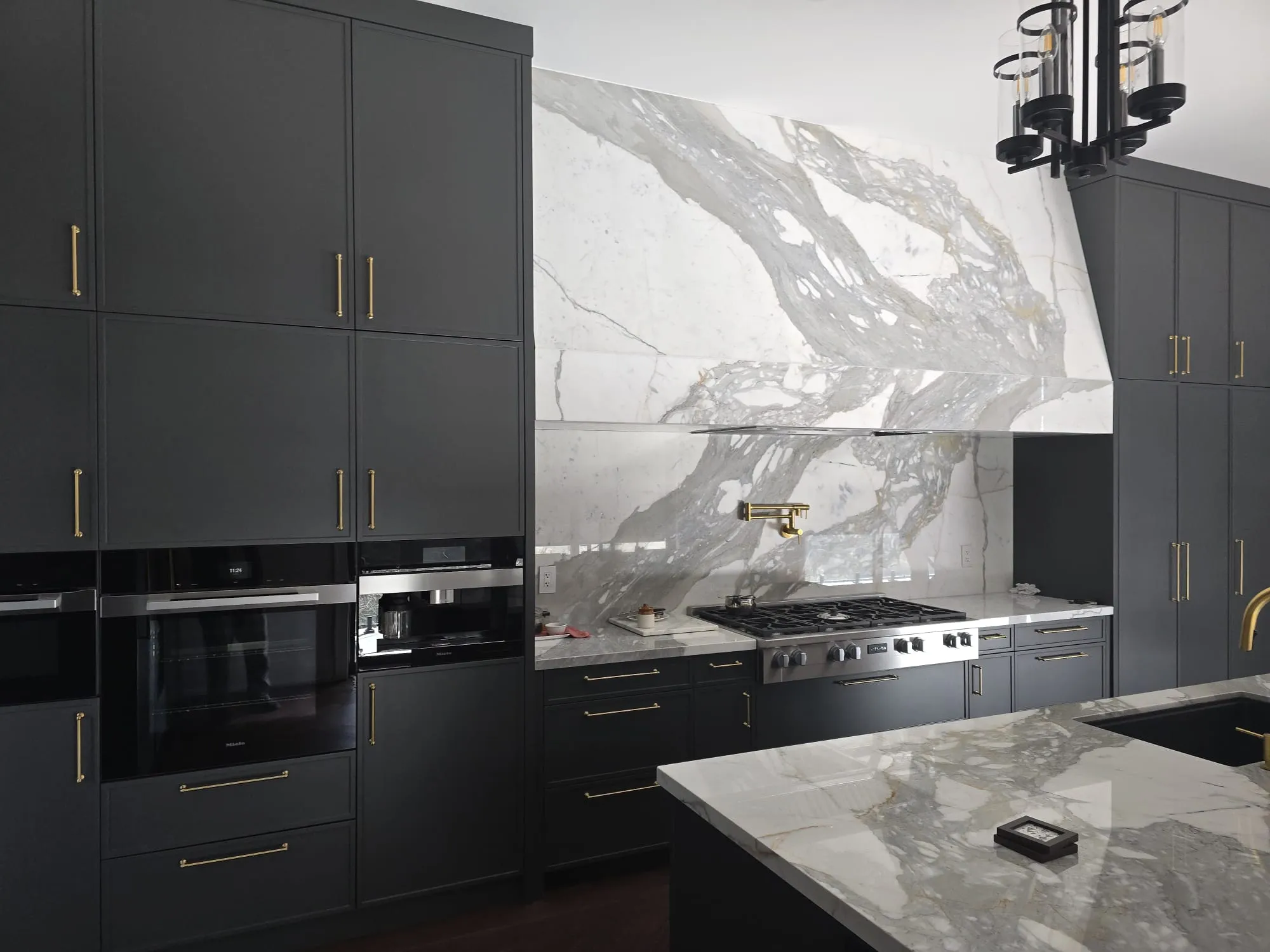 Dark kitchen cabinetry with a dramatic marble backsplash