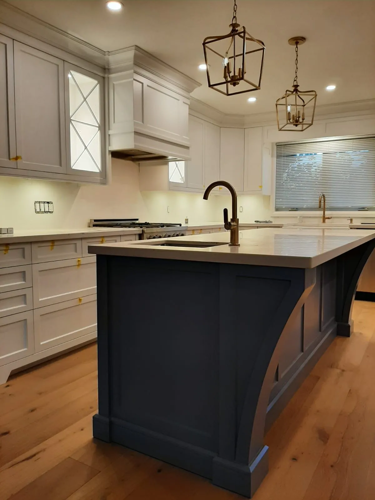 Traditional white kitchen with a dark island and glass cabinet doors